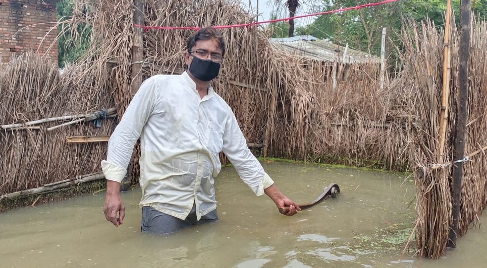 Local youth showing hand pump submerged in flood