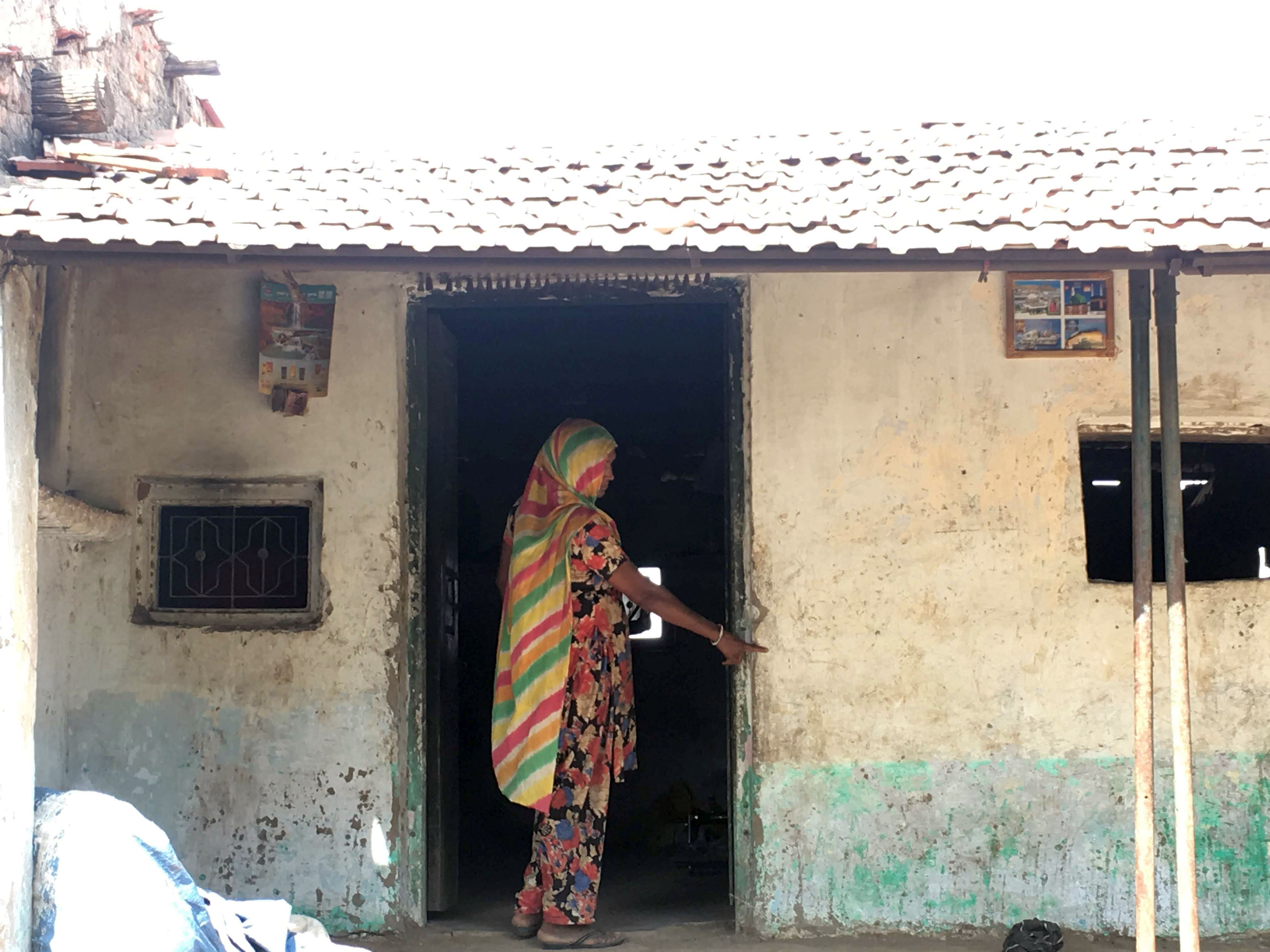 A woman resident of Rakhadiya vaand showing the water level mark that had flooded the area during 2017 (Image: Chetna Verma)