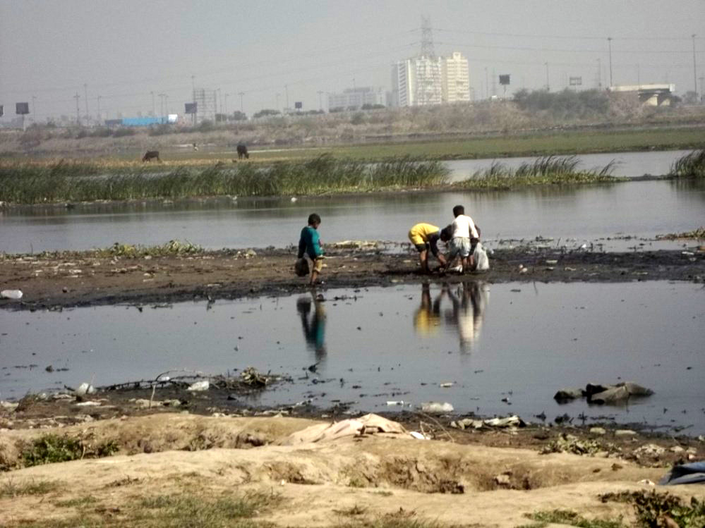 Children playing with garbage on the bank of river Yamuna