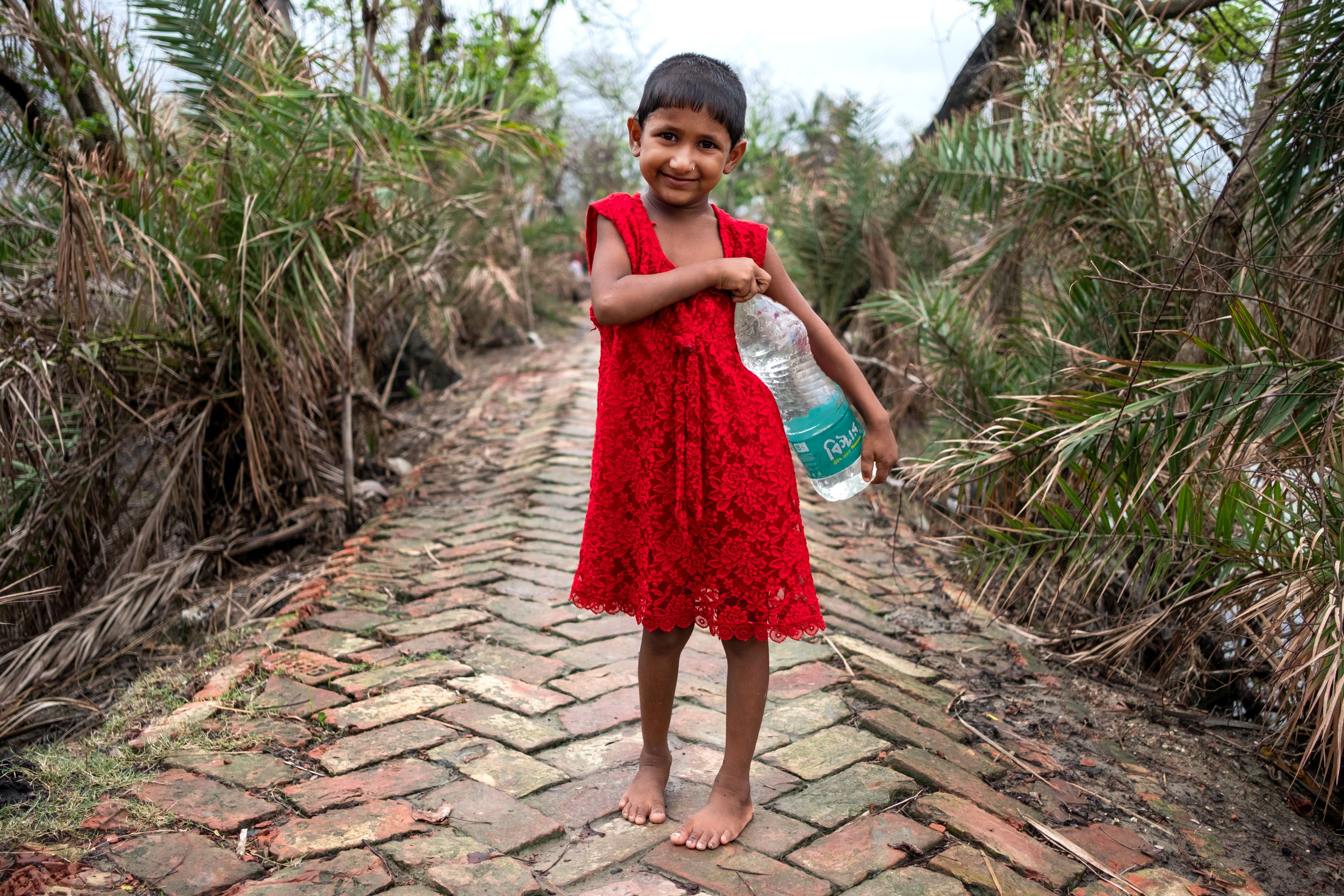 Rinki Bera is holding a bottle of packaged drinking water. This costs her family around sixty to hundred rupees putting the family under an immense financial strain. Aila had inflicted excessive damage to the people but Amphan combined with the coronavirus pandemic has taken away almost everything from them. (Image: WaterAid, Subhrajit Sen)  