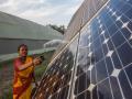 A woman cleaning a solar panel (Image Source: IWMI)