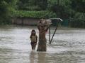 A woman wades through knee-deep water with her belongings. (Picture courtesy - 101Reporters) (Source: IWP Flickr photos)