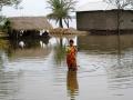 A woman wades through a flooded road. (Source: IWP Flickr photos)