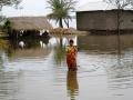 A woman wades through a flooded road. (Source: IWP Flickr photos)