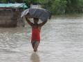 A man wades through knee-deep water with his belongings during flood. (Source: 101Reporters)