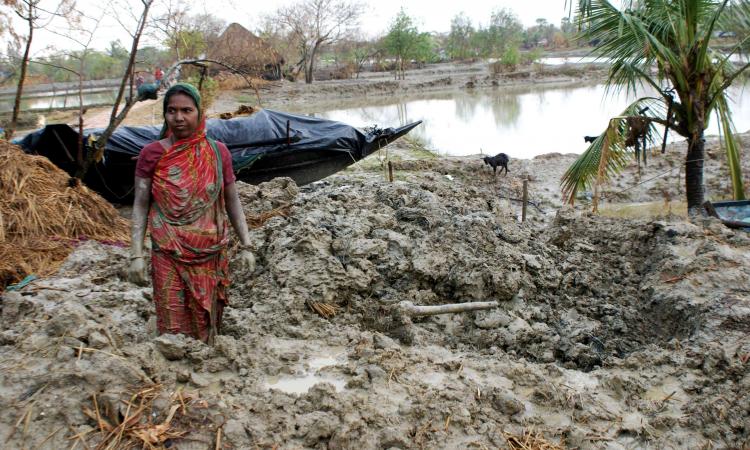 A woman searching for her utensils in debris of her house which collapsed after Cyclone Aila (Image: Anil Gulati, Wikimedia Commons)