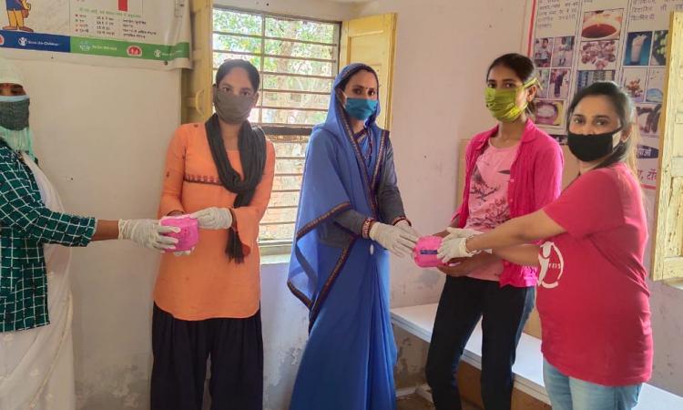 ज़रूरतमंद किशोरियों को नैपकिन बांटती समूह की सदस्या