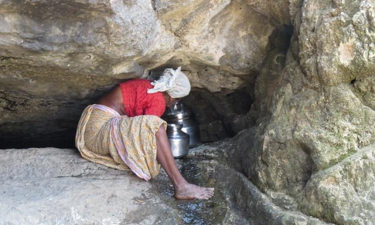 अकोले के एक स्प्रिंग से पानी के लिये जद्दोजहद करती महिला