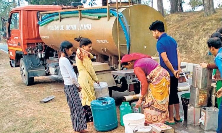 अल्मोड़ा के डिनापानी गांव के ग्रामीण टैंक से पानी लेते हुए