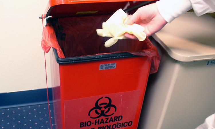 A lab technician discarding disposable gloves (Image: CDC/Kimberly Smith, Christine Ford acquired from Public Health Image Library)