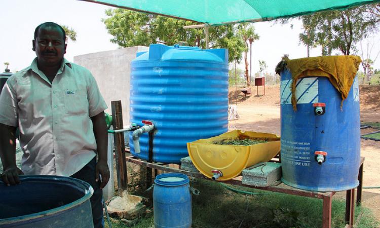 Alagesan with the barrel used to ferment cow dung 