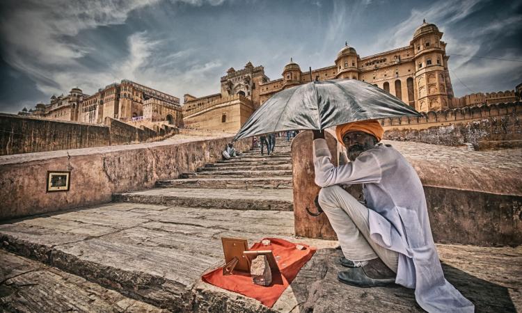 A man sits under the scorching heat of the sun in front of Amer fort in Jaipur. The city landscape is now dominated by heat trapping materials that prevent its cooling through evapotranspiration. (Picture courtesy: Prabhu B Doss, Flickr Commons: CC-By-NC-ND-2.0)