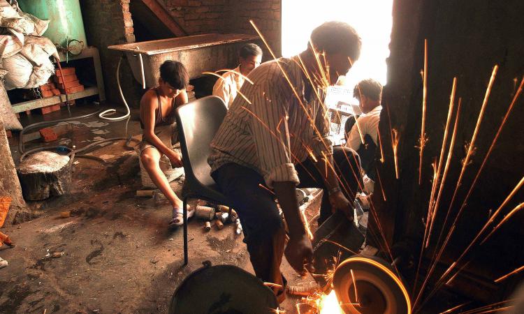 Boys sort discarded computer parts as sparks fly from a grinding machine. (Image: Greenpeace, Flickr Commons; CC BY-ND 2.0)