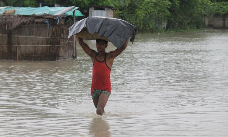 A man wades through knee-deep water with his belongings. (Source: 101Reporters)
