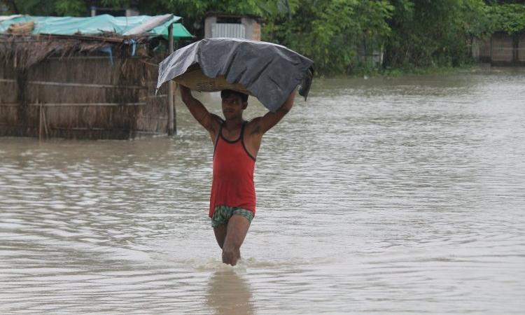 A man wades through knee-deep water with his belongings during flood. (Source: 101Reporters)