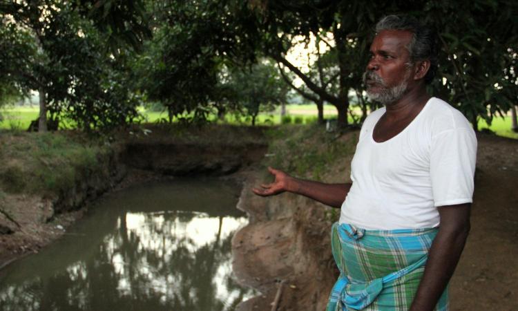Farmer Elumalai looks on at his pond
