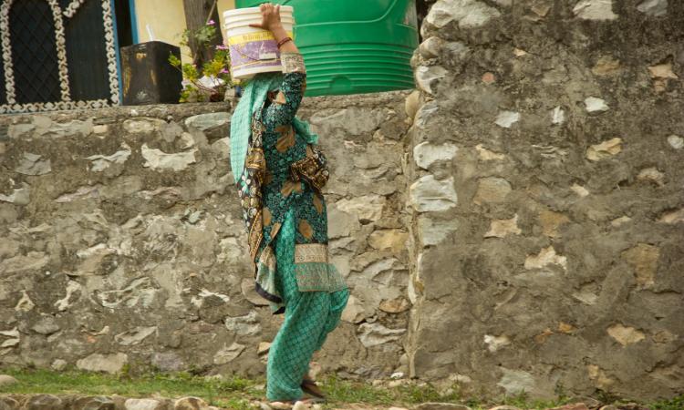 Rajni Devi carries water to her home. (Source: 101Reporters)