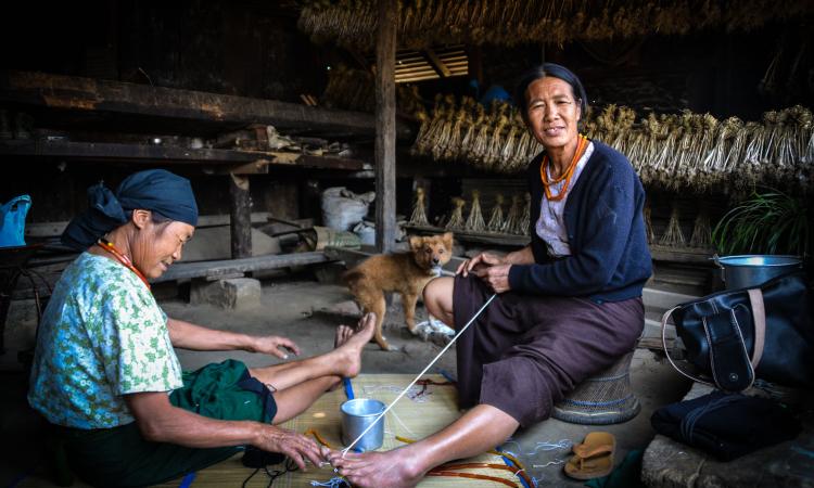 Women in Khonoma tying beads to make necklaces